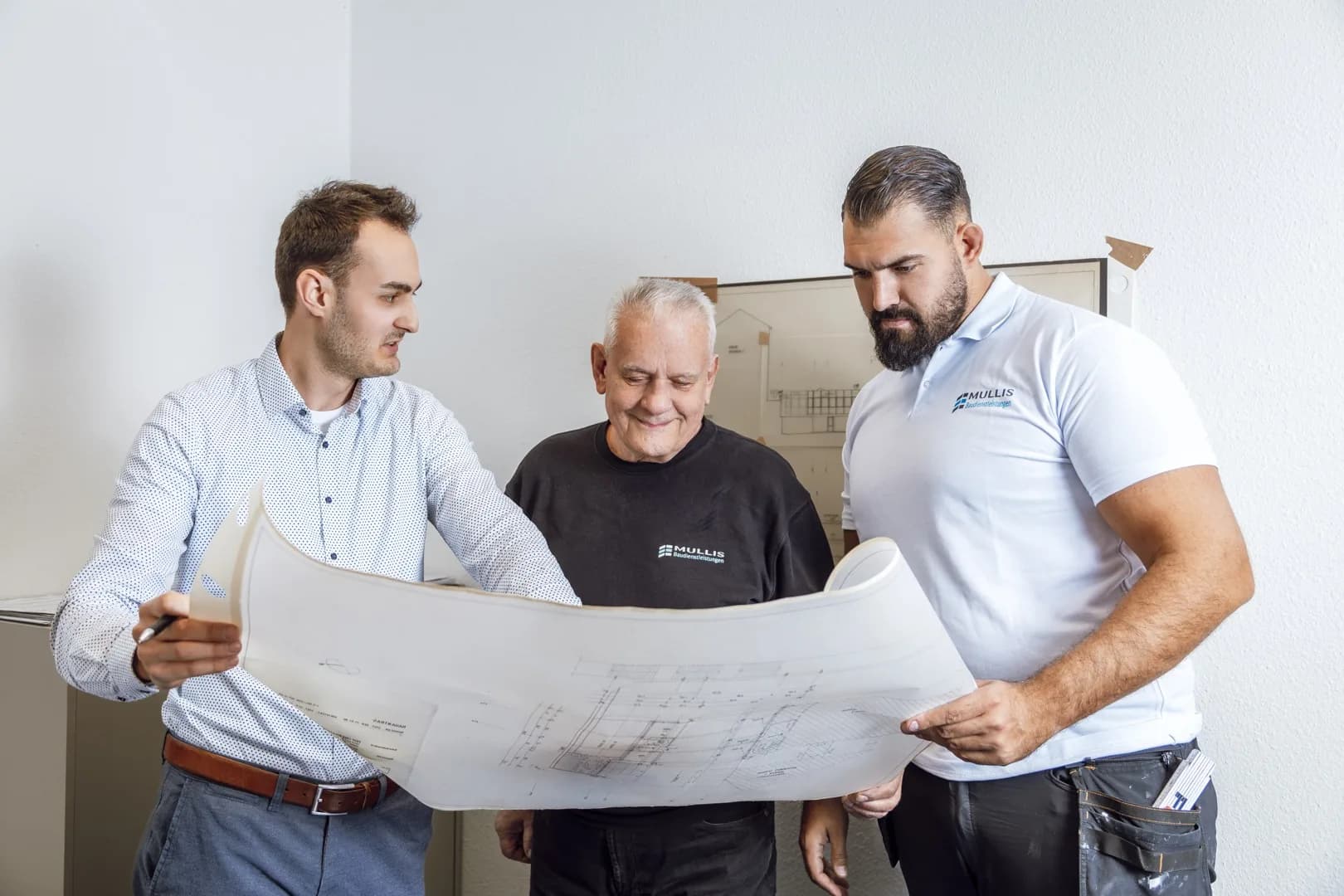 Drei Mitarbeiter der Mullis GmbH besprechen einen Bauplan