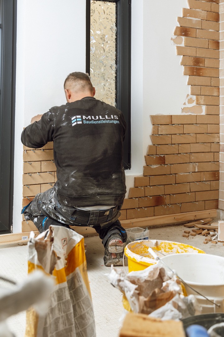 Mullis-Arbeiter bringt während der Renovierung Ziegelfliesen an einer Innenwand an.